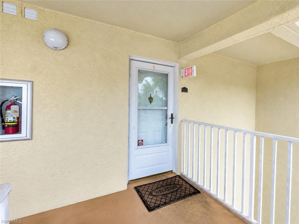Entryway with a white screen door, textured stucco walls, and a white metal railing