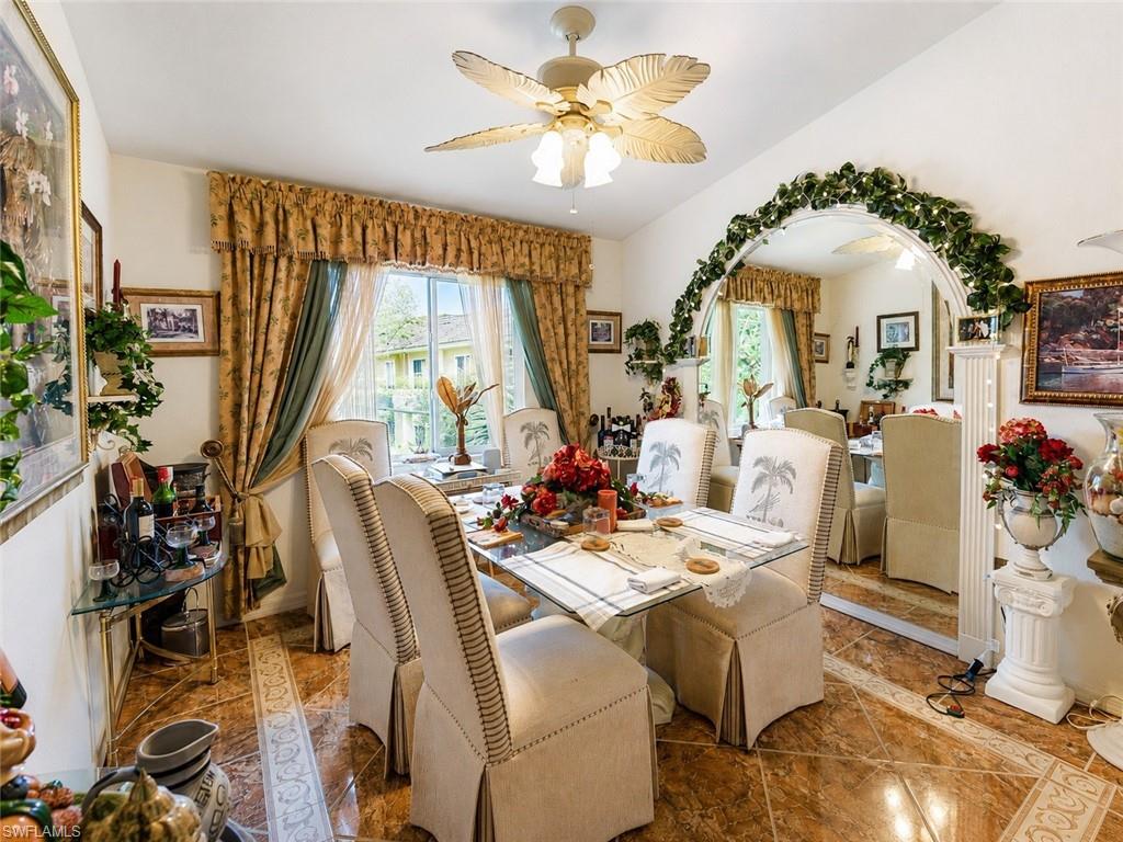 Formal dining area featuring tile flooring with decorative inlay, a ceiling fan with leaf-shaped blades, and an arched mirror accent wall