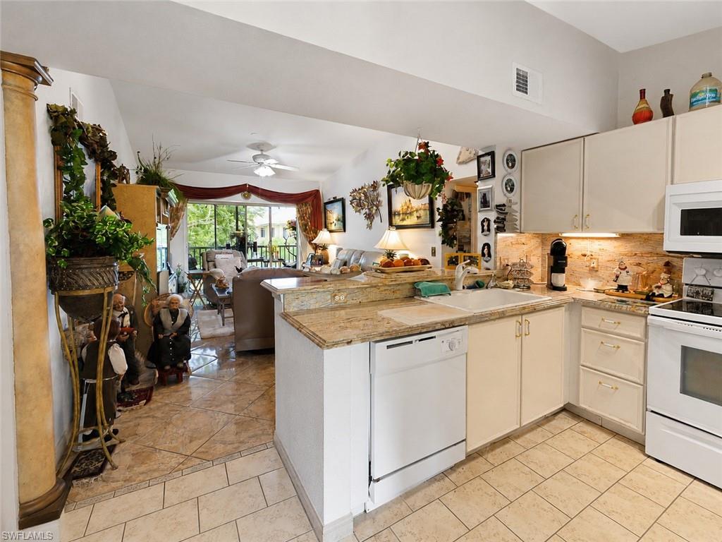 Kitchen featuring light-toned cabinetry, a double basin sink, and granite countertops