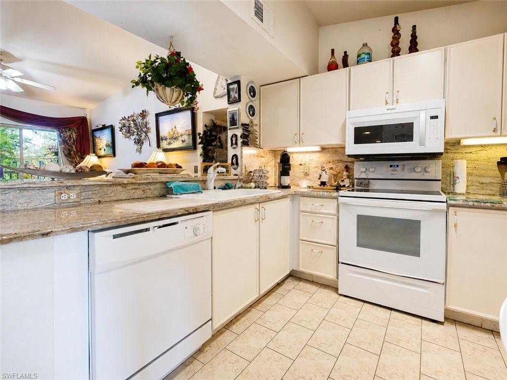 Kitchen featuring white cabinetry, stone countertops, integrated white dishwasher, and tile flooring