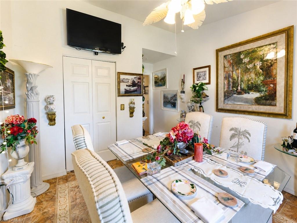 Dining area featuring a glass-top table, upholstered chairs with decorative accents, and tiled flooring