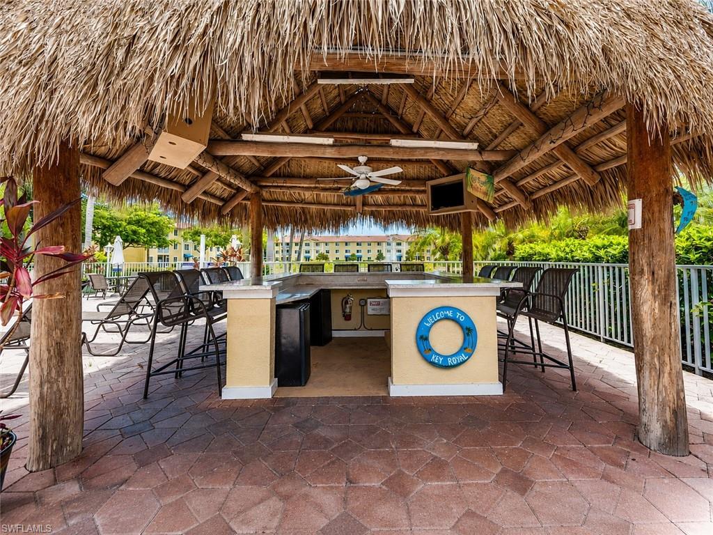 Thatch-roofed cabana featuring a built-in outdoor bar with countertop seating and a ceiling fan