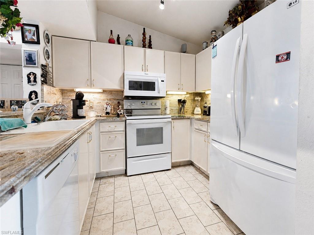 Kitchen featuring white cabinetry, light-toned granite countertops, and a full suite of white appliances