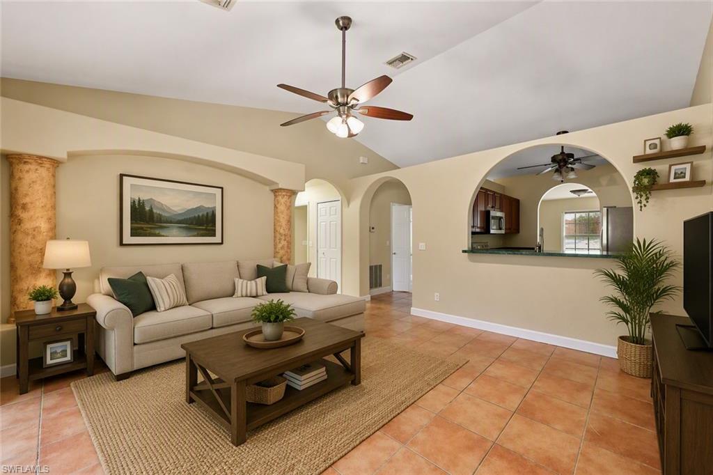 Spacious living room showcasing soaring ceilings with ceiling fan, arched architectural details, and abundant natural light from multiple windows
