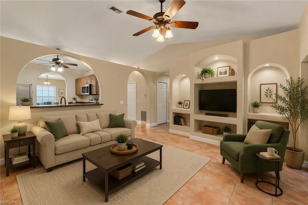 Open-concept living space featuring vaulted ceilings, ceiling fan, and tile flooring