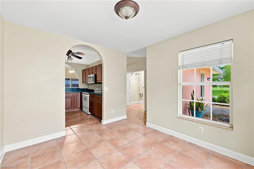 Spacious room featuring tile flooring, an arched entryway to the kitchen, and a single window with blinds