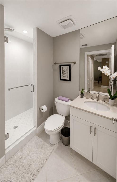 Contemporary bathroom featuring a glass-enclosed shower with white subway tile, a white vanity with recessed panel cabinetry, a light-toned countertop, and tile flooring