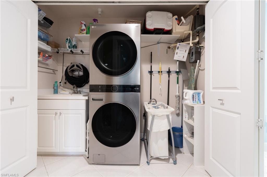 Laundry closet featuring cabinet space, stacked washer / drying machine, and light tile patterned flooring