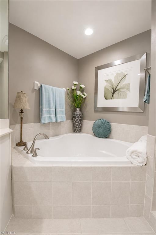 Corner soaking tub with tile surround and brushed nickel fixtures