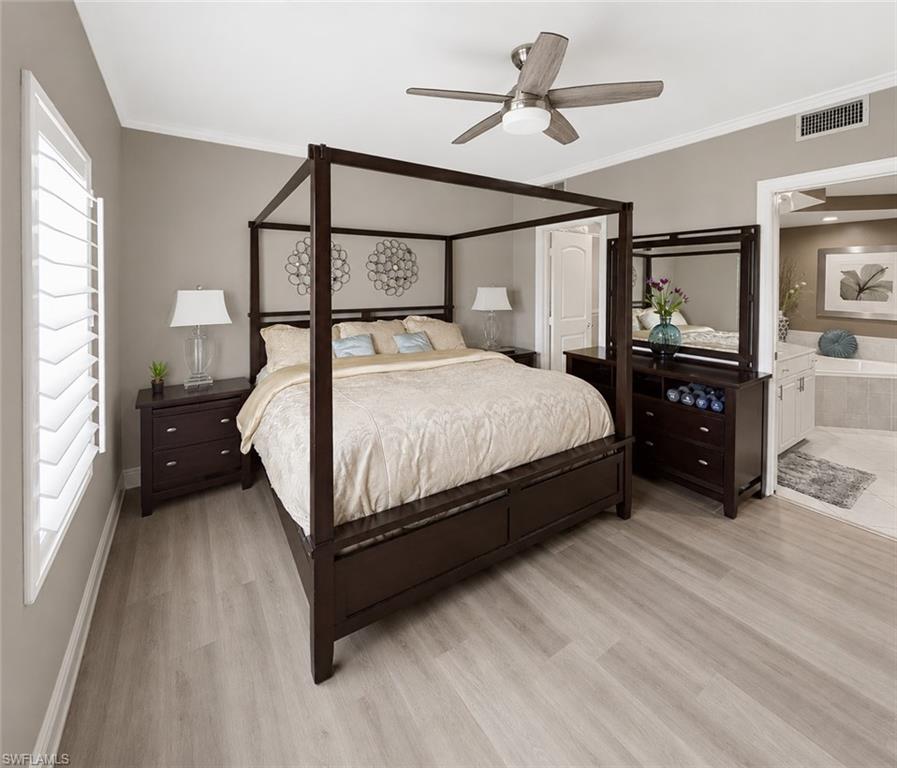Bedroom featuring light wood-finish flooring, crown molding, a ceiling fan with integrated lighting, and window shutters