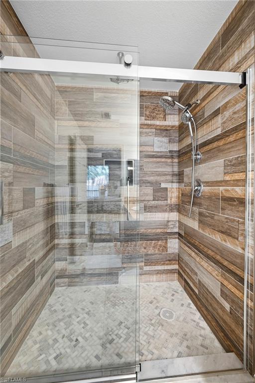 Glass-enclosed shower featuring wood-finish wall tile and a mosaic tile floor