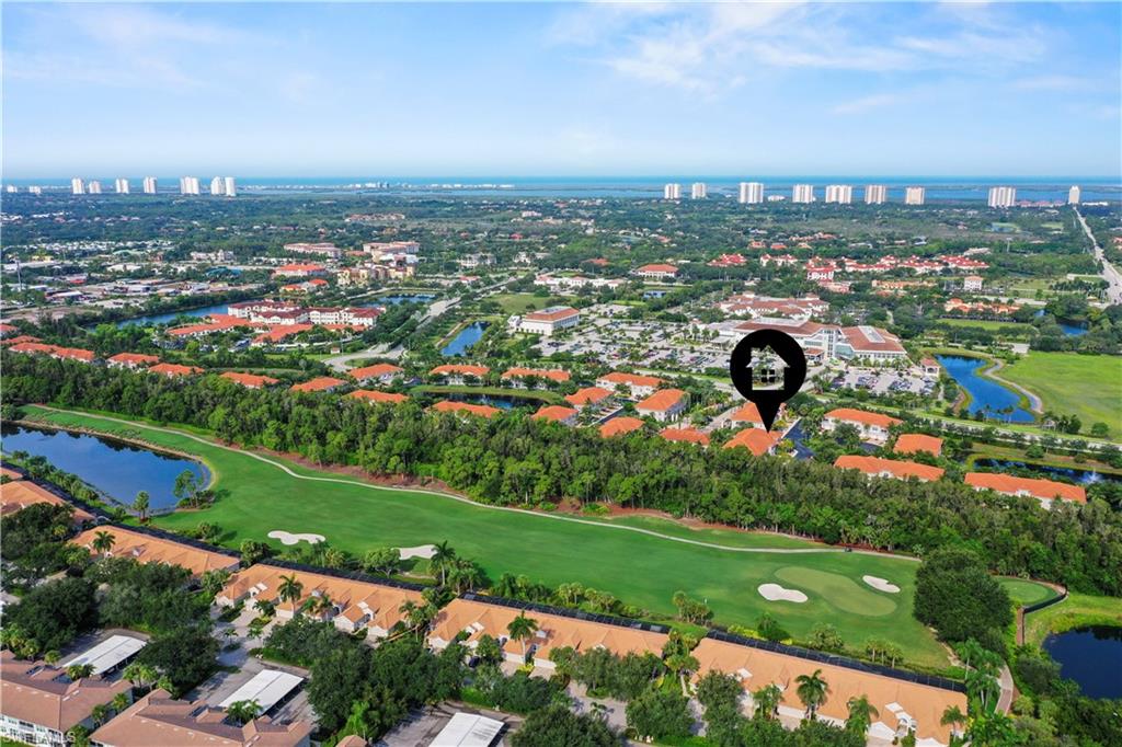 Expansive aerial showcasing a golf course property with verdant fairways, multiple water features, and surrounding residential structures