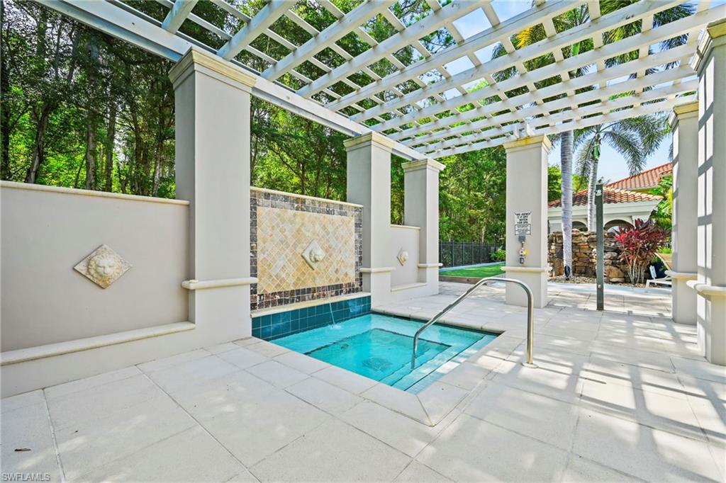 Spa area featuring a tiled water feature, a white pergola, and light-toned paving