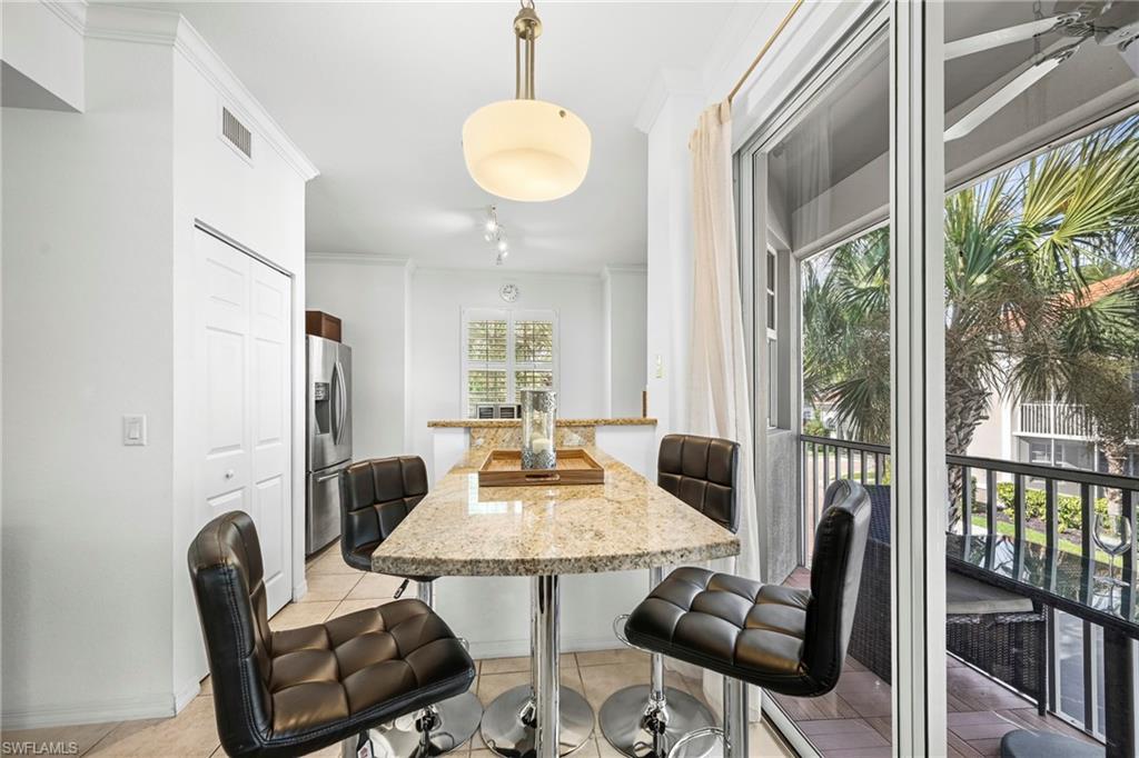Kitchenette featuring a granite-look breakfast bar with pendant lighting, stainless steel refrigerator, and tiled flooring