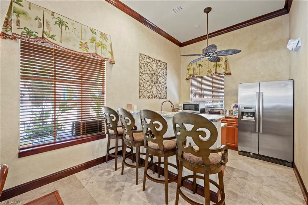 Kitchenette featuring a built-in island with seating, stainless steel refrigerator, integrated sink, and ceiling fan