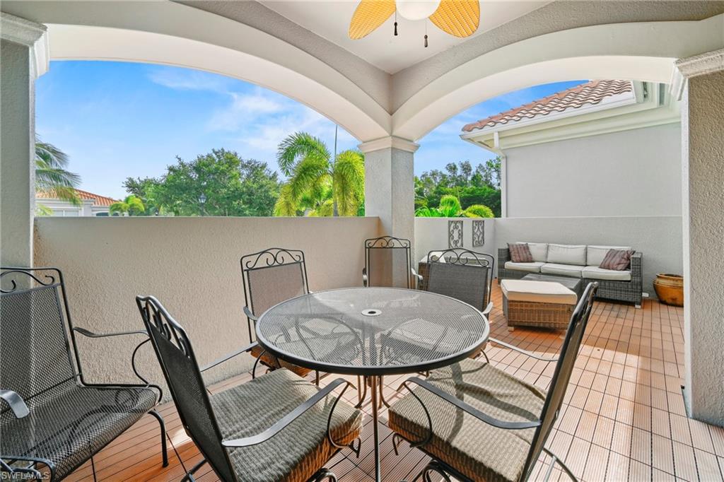 Spacious outdoor patio featuring wood-finish flooring, a ceiling fan, and arched architectural details