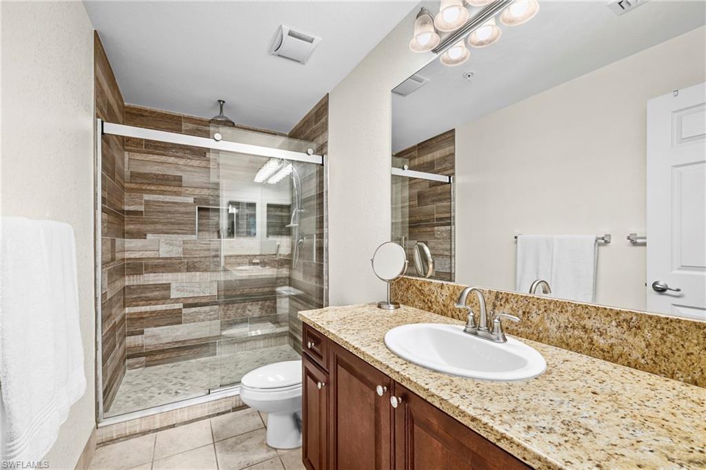 Bathroom featuring a wood-finish tile shower with clear glass sliding doors, a built-in shower niche, and a rain showerhead