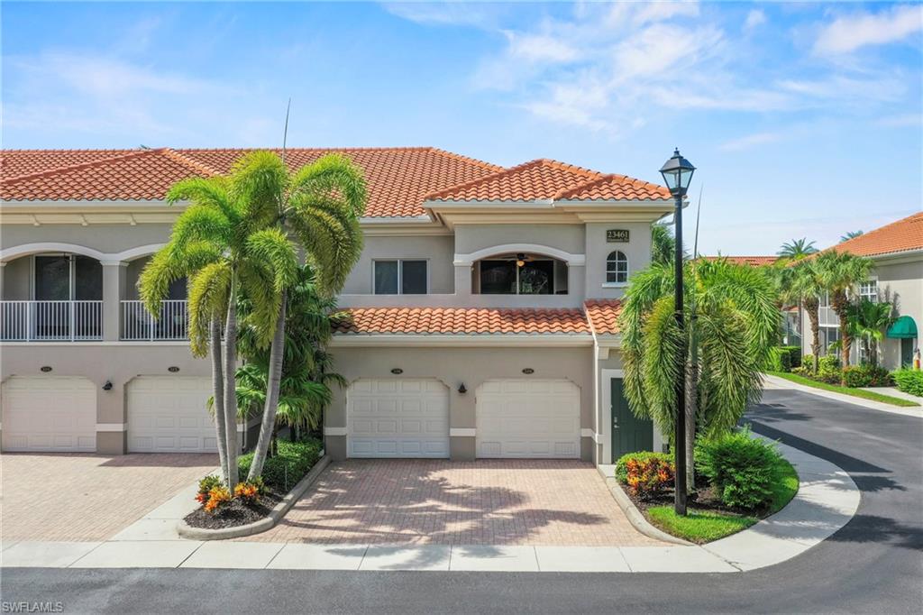 Mediterranean-inspired exterior featuring a terracotta tile roof, multiple garage bays, and a second-story balcony with white railings