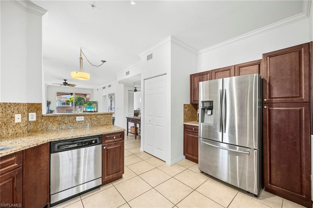 Kitchen featuring granite countertops, wood cabinetry, stainless steel appliances, and tile flooring