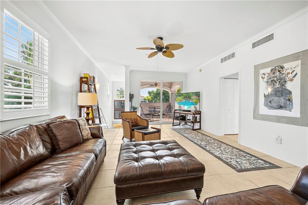 Spacious living area featuring tile flooring, crown molding, and a ceiling fan