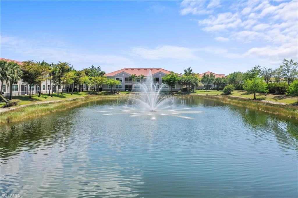 Expansive water feature with a central fountain, bordered by green landscaping and palm trees