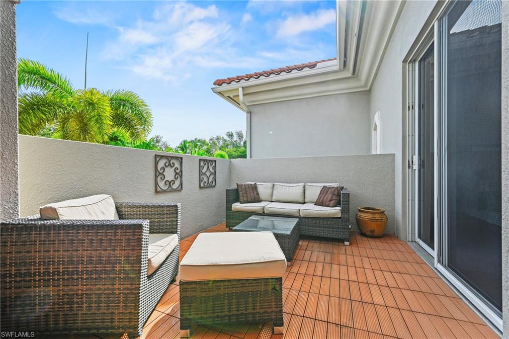 Expansive outdoor patio featuring wood-finish flooring, a stucco privacy wall, and a sliding glass door entry