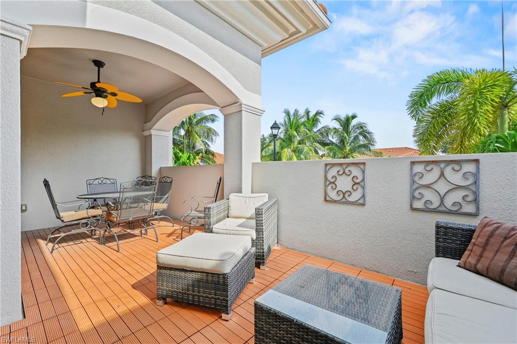 Covered patio featuring wood-finish flooring, an arched entryway, and a ceiling fan with integrated lighting