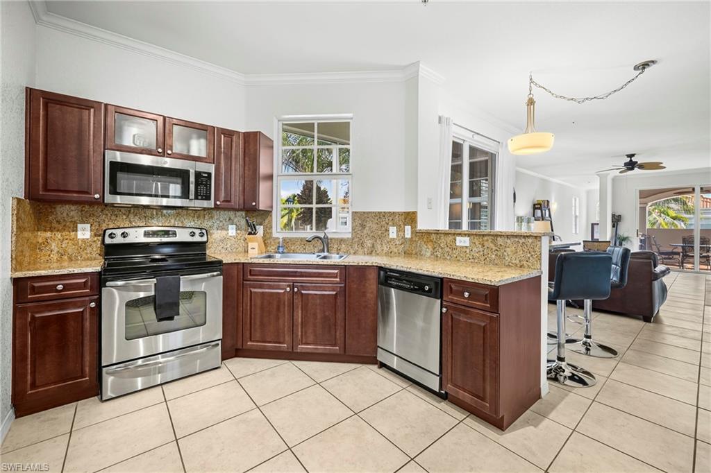 Kitchen featuring wood cabinetry, stainless steel appliances, speckled stone countertops, and a tile backsplash