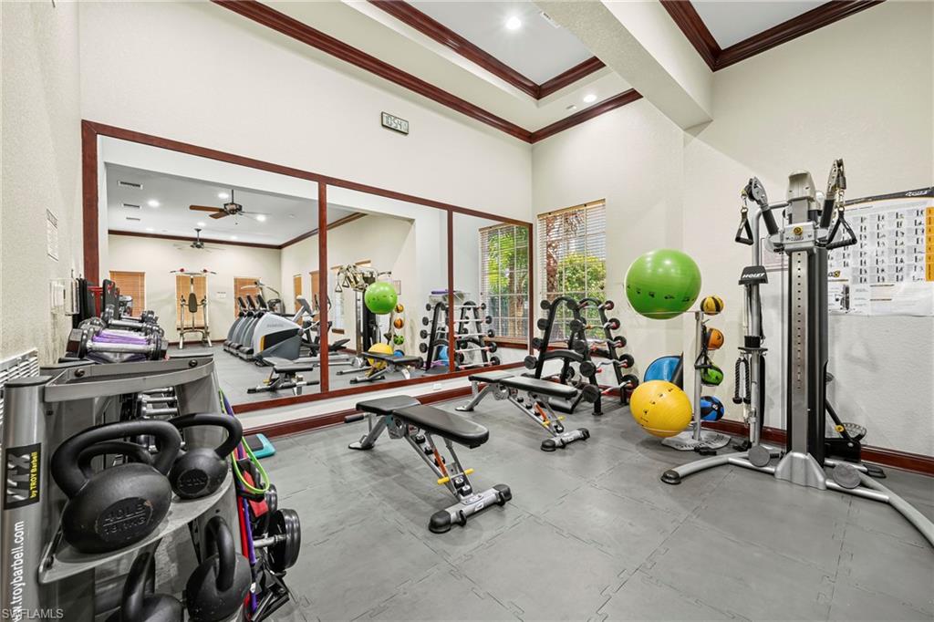 Dedicated fitness room featuring interlocking rubber floor tiles, a mirrored wall, and recessed ceiling lighting