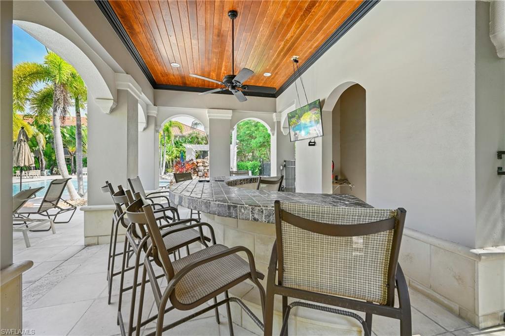 Outdoor bar area featuring a tiled countertop, wood-finish ceiling, and arched architectural details