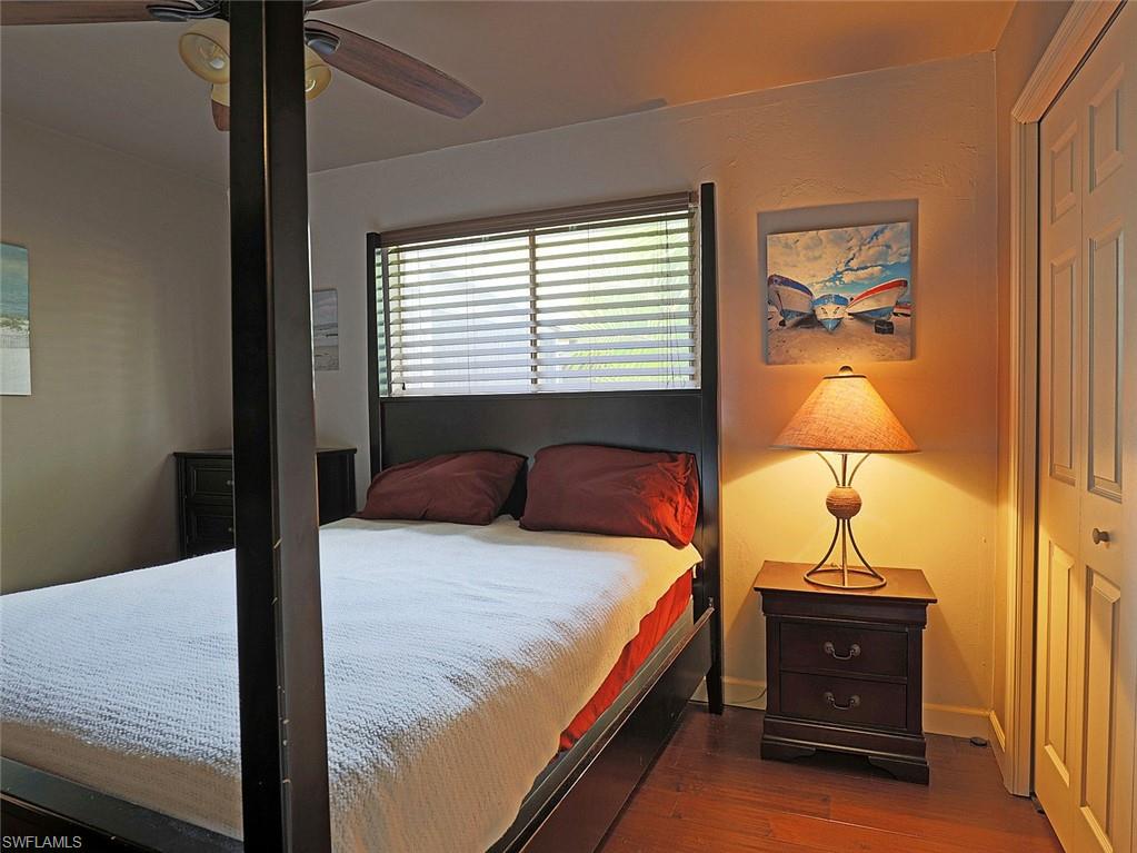 Bedroom featuring wood-finish flooring, a ceiling fan with integrated lighting, and a window with horizontal blinds