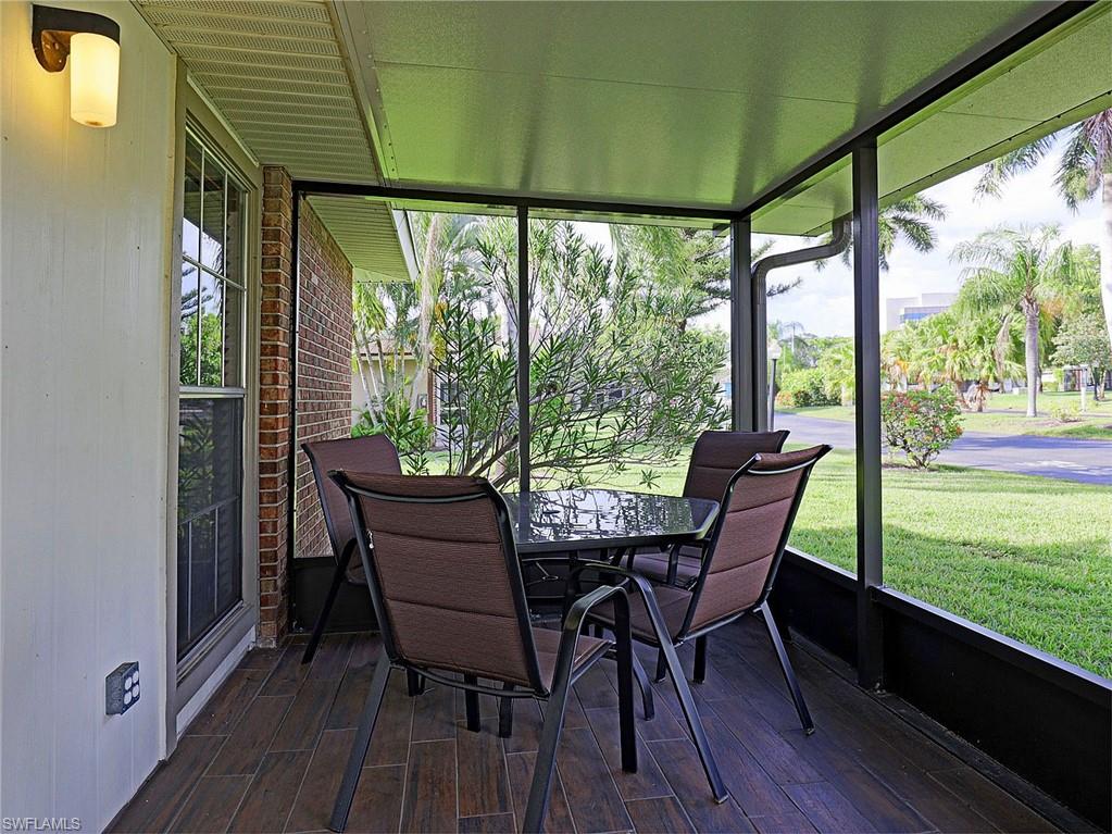Screened patio featuring wood-finish flooring, a white vertical panel exterior wall, and a brick exterior wall