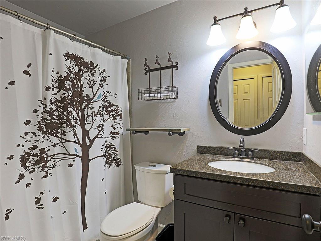 Bathroom vanity featuring a dark wood-finish cabinet with a granite-style countertop, undermount sink, and dark-toned faucet