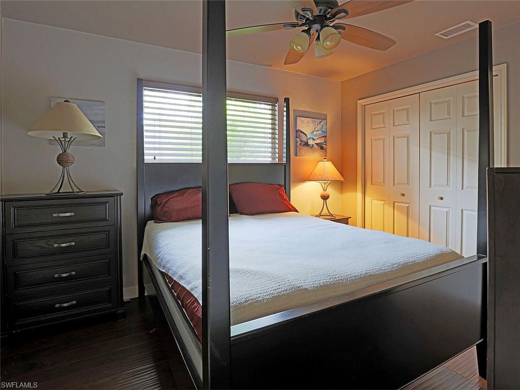 Bedroom featuring dark wood-finish flooring, a ceiling fan with integrated lighting, and a window with horizontal blinds