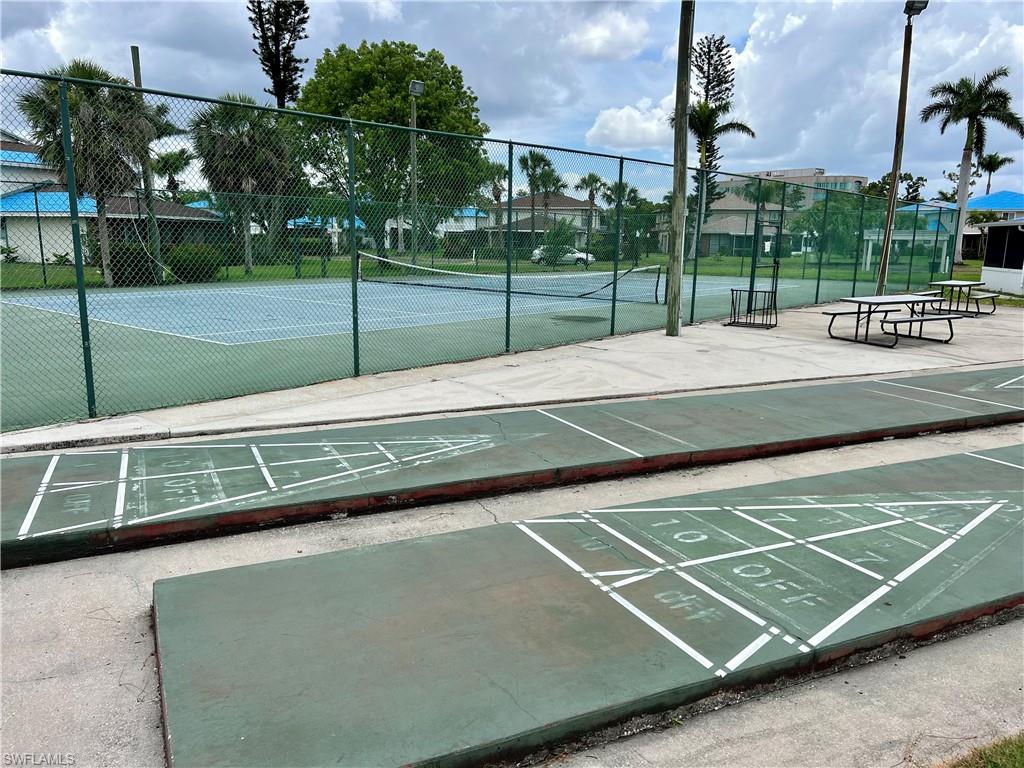 Recreational area featuring two shuffleboard courts with painted markings and an enclosed tennis court with a blue surface