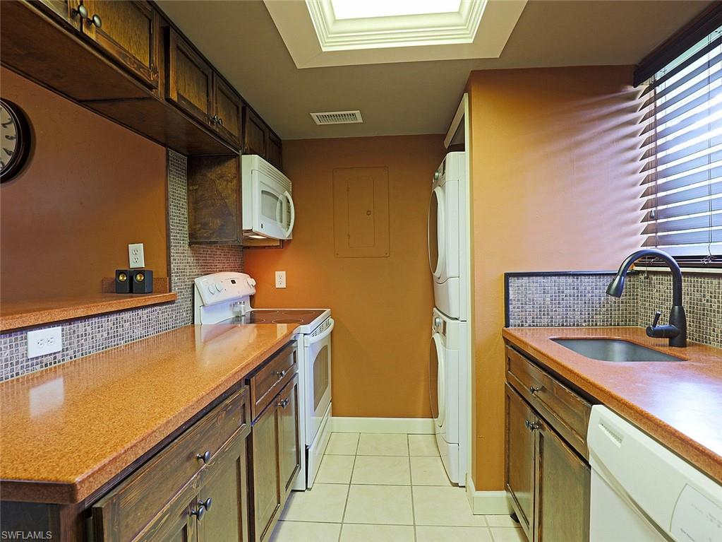 Galley kitchen featuring wood cabinetry, stone-finish countertops, and a mosaic tile backsplash