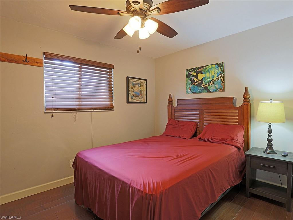 Bedroom featuring dark wood-finish flooring, a ceiling fan with integrated lighting, and a window with horizontal blinds
