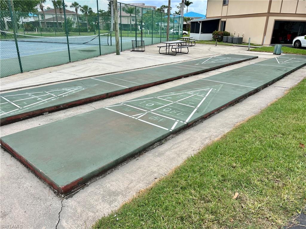 Dual shuffleboard courts with painted scoring lines on a concrete pad, surrounded by a manicured grass border