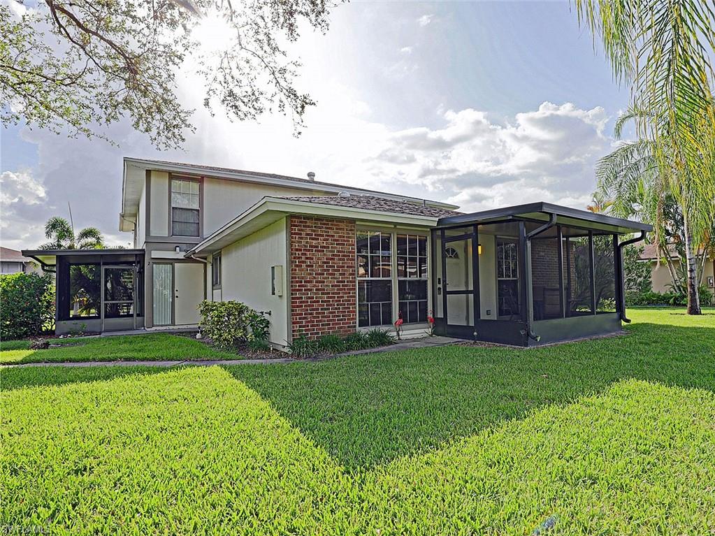 Exterior featuring a brick facade accent, two screened enclosures, light-toned siding, and a well-maintained lawn