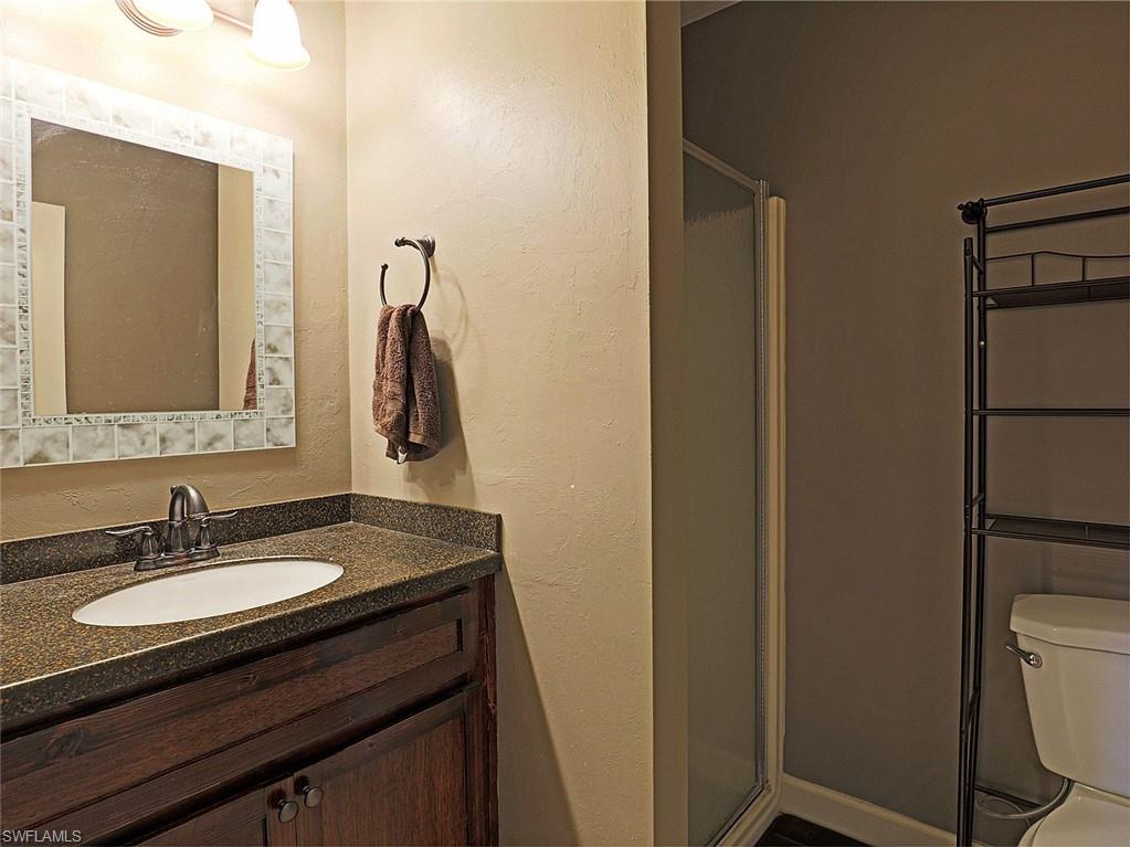 Bathroom featuring a dark wood-finish vanity with a built-in sink, stone-finish countertop, and a tiled mirror frame