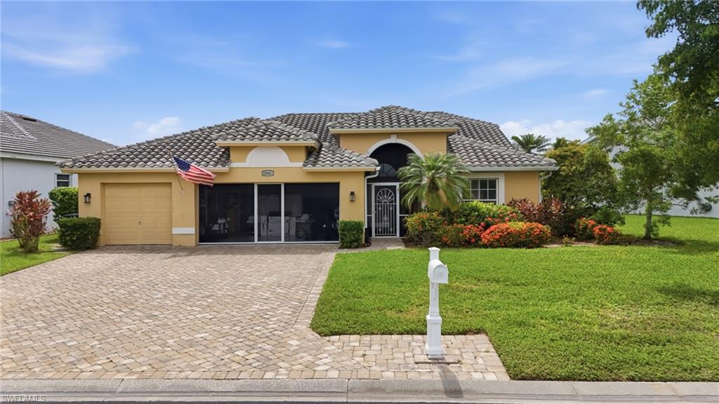 Exterior featuring a paver driveway, an arched entry, a screened front porch, a tile roof, and extensive landscaping