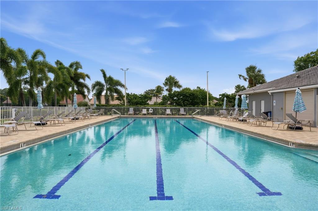 Outdoor swimming pool featuring lap lanes, surrounding paver deck, and adjacent clubhouse