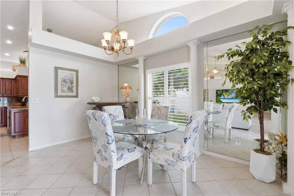 Dining area featuring tile flooring, a decorative chandelier, and a large window with white plantation shutters