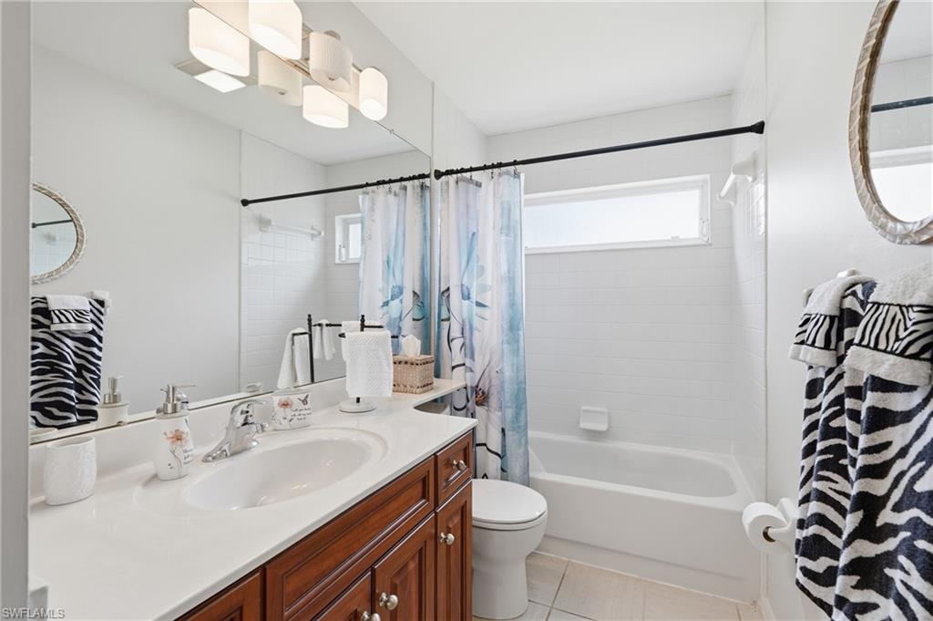 Full wall-length mirror above a single vanity with wood-finish cabinetry and a white countertop