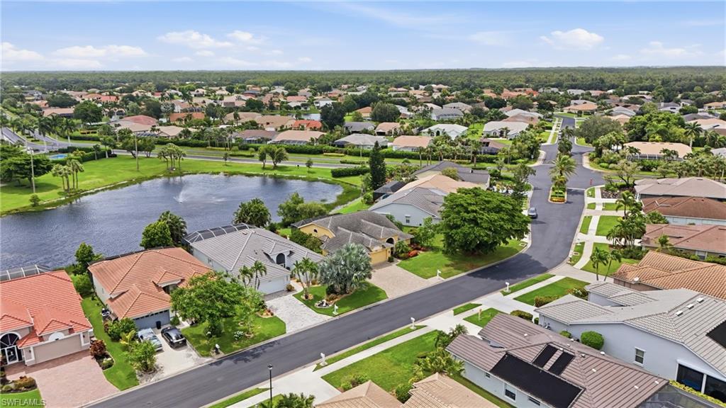 Residential neighborhood featuring a prominent pond with a fountain, mature landscaping, and curved roadways