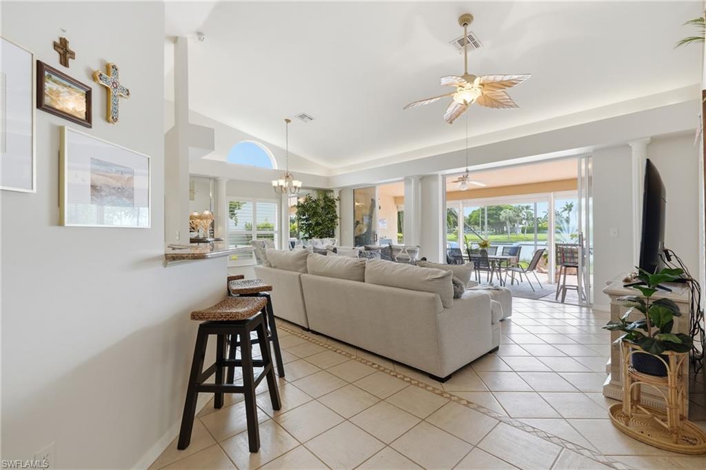 Open-concept living area with tile flooring and decorative inlay, featuring a breakfast bar with stone countertop