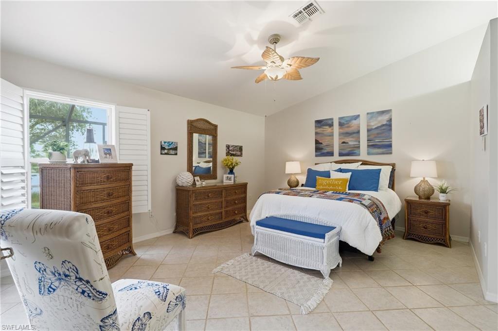 Vaulted ceiling room featuring tiled flooring, a ceiling fan with leaf-shaped blades, and a window with white louvered shutters
