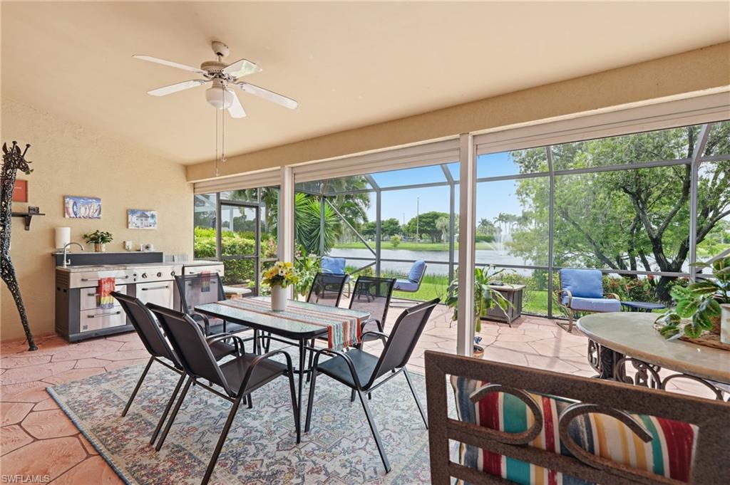 Screened patio featuring an outdoor kitchen with an integrated grill, a ceiling fan, and direct water frontage