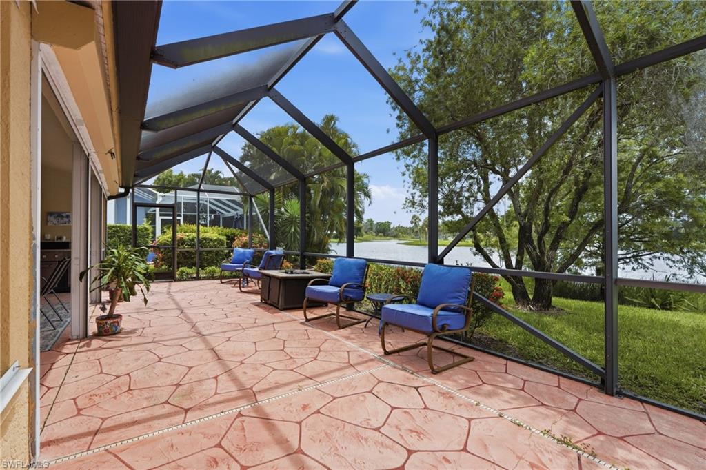 Screened patio featuring stamped concrete flooring, a partial lakefront setting, and mature landscaping