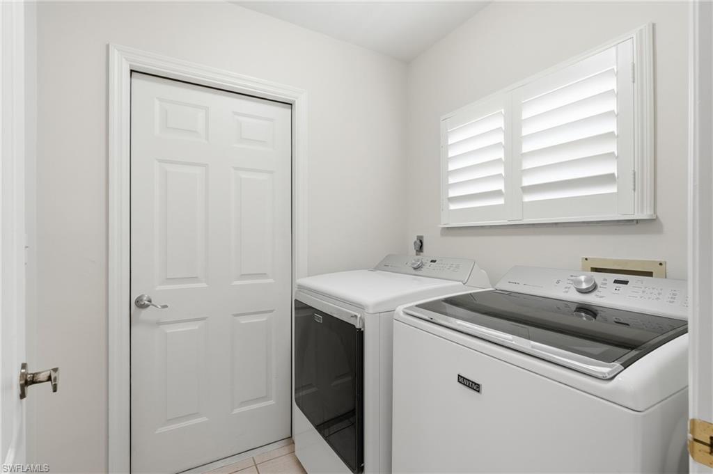 Dedicated laundry space featuring white plantation shutters and tiled flooring